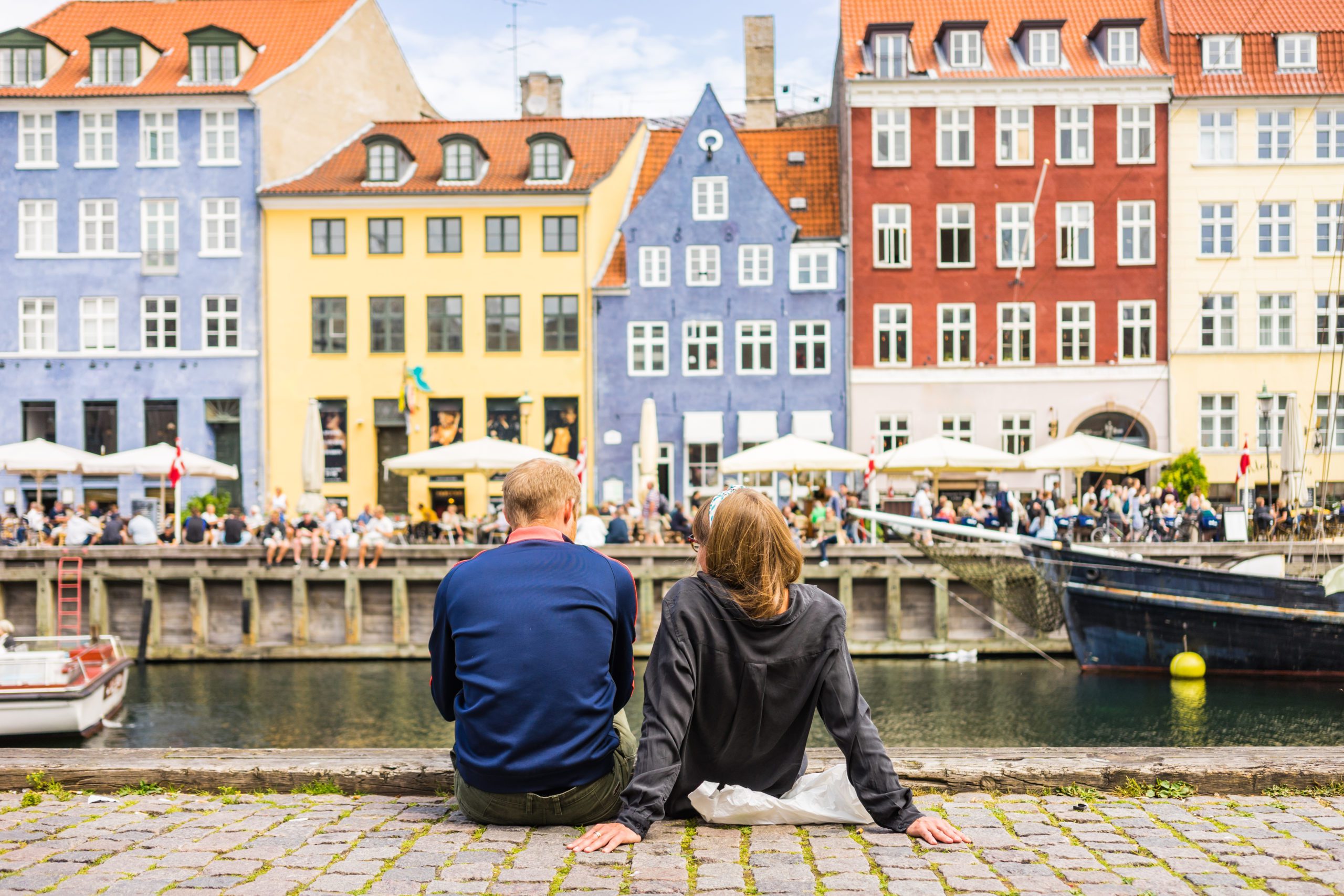 Couple sitting by a riverbank in Copenhagen